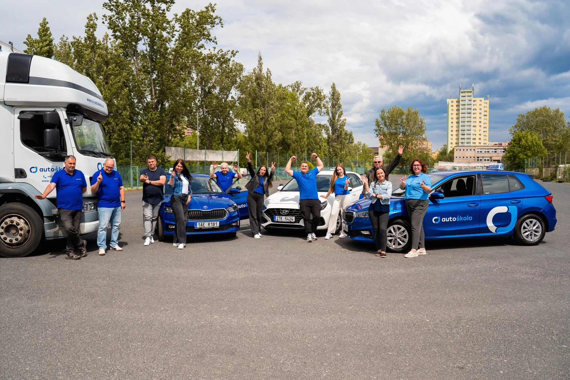 Celý tým CJ Autoškoly mává u výcvikových vozů na cvičišti